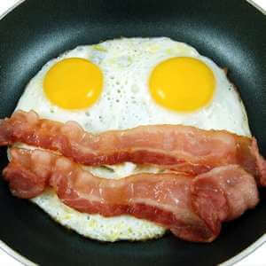 eggs and bacon frying in a pan